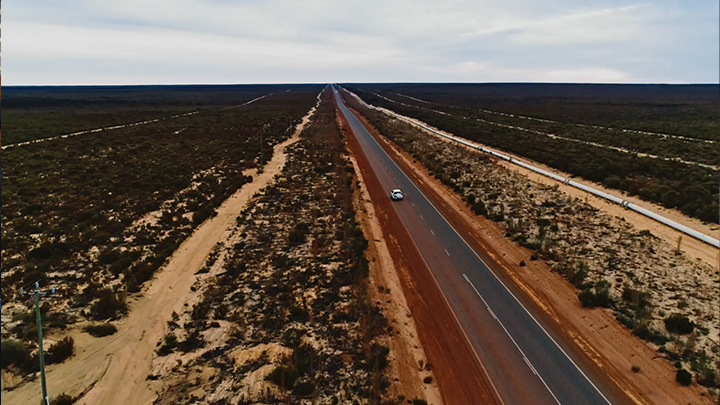 A wide angle shot of the country with a road in the centre leading up and to the left.